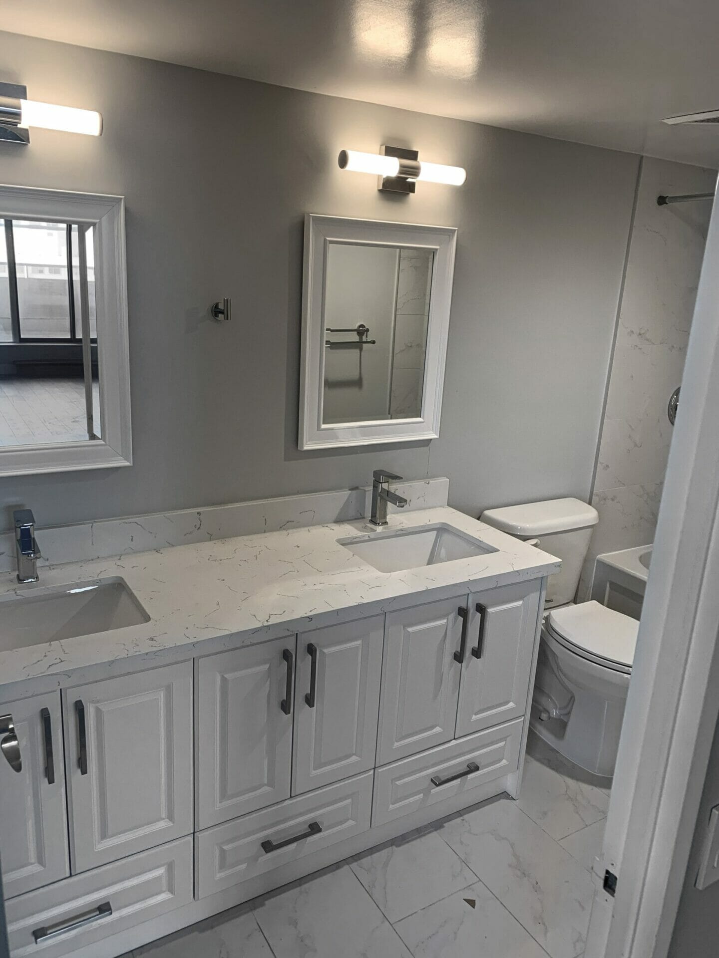 Desa Contracting, Restoration, and Janitorial Services'in Toronto gorgeously renovated bathroom at 750 Bay Street Condo features two mirrors, LED lighting, and a spotless sink cabinet.