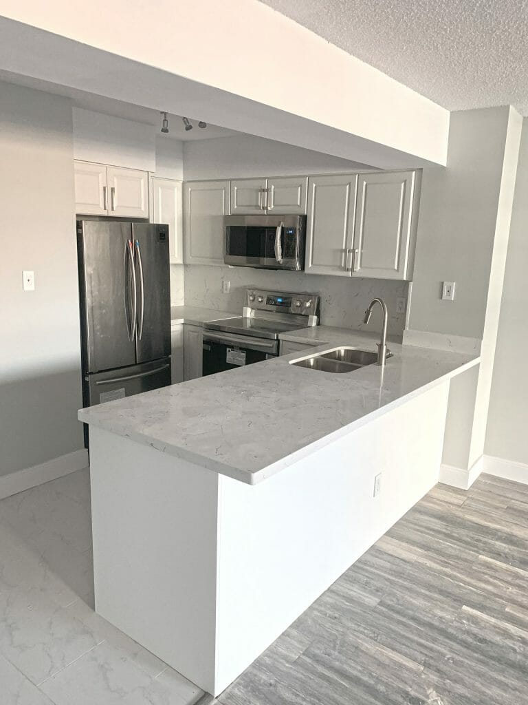 Completely renovated kitchen by Desa Contracting, Restoration, and Janitorial Services featuring a cook top, a double-door refrigerator, a microwave, and an island.