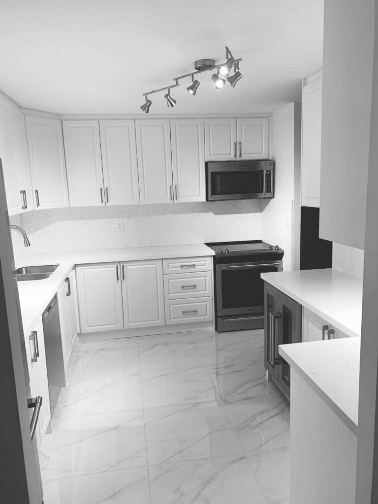 Displaying a Spotless, Newly Renovated Kitchen with a Cooktop, Microwave, Sink, and Cabinets with Plenty of Storage by Desa Contracting, Restoration, and Janitorial Services in Toronto.