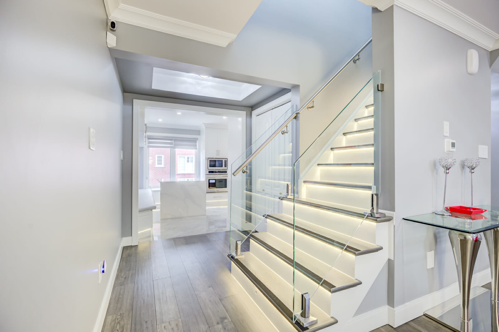 In the Toronto home restoration by Desa Contracting and Restoration, you'll find a staircase illuminated with LED lights, a modern kitchen, and a convenient side table.