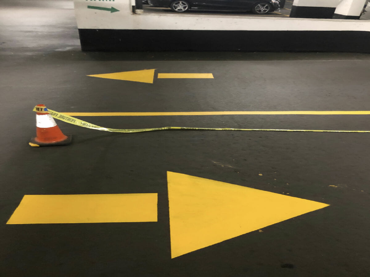 A closer look at a parking garage underground where Desa Contracting, Restoration, and Janitorial Services recently painted direction arrows at a condo in Toronto that operate as indicators for vehicles to travel to and from their corresponding parking spaces.