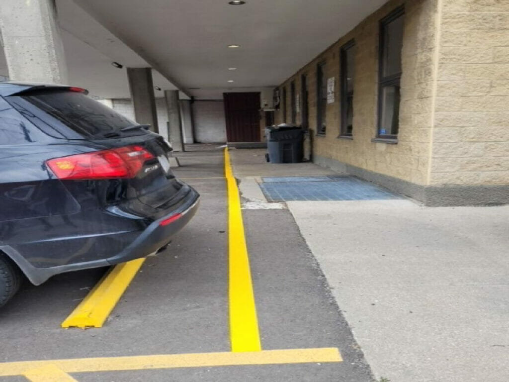 Showcasing four parking lights, three pillers, and a parked car by Desa Contracting, Restoration, and Janitorial Services under a condo apartment in Toronto.