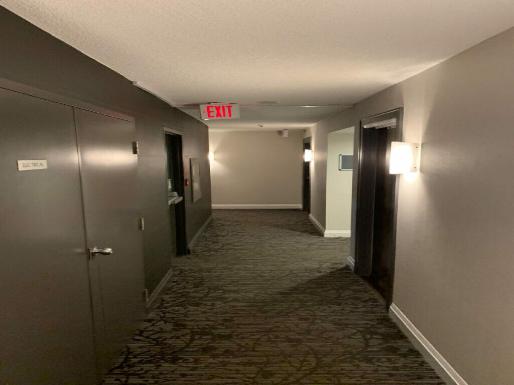 Featuring a Well Lit Hallway, an Electrical Room, and Two Refurbished Doors with Polished Wood Side Frames by Desa Contracting, Restoration, and Janitorial Services in Toronto.