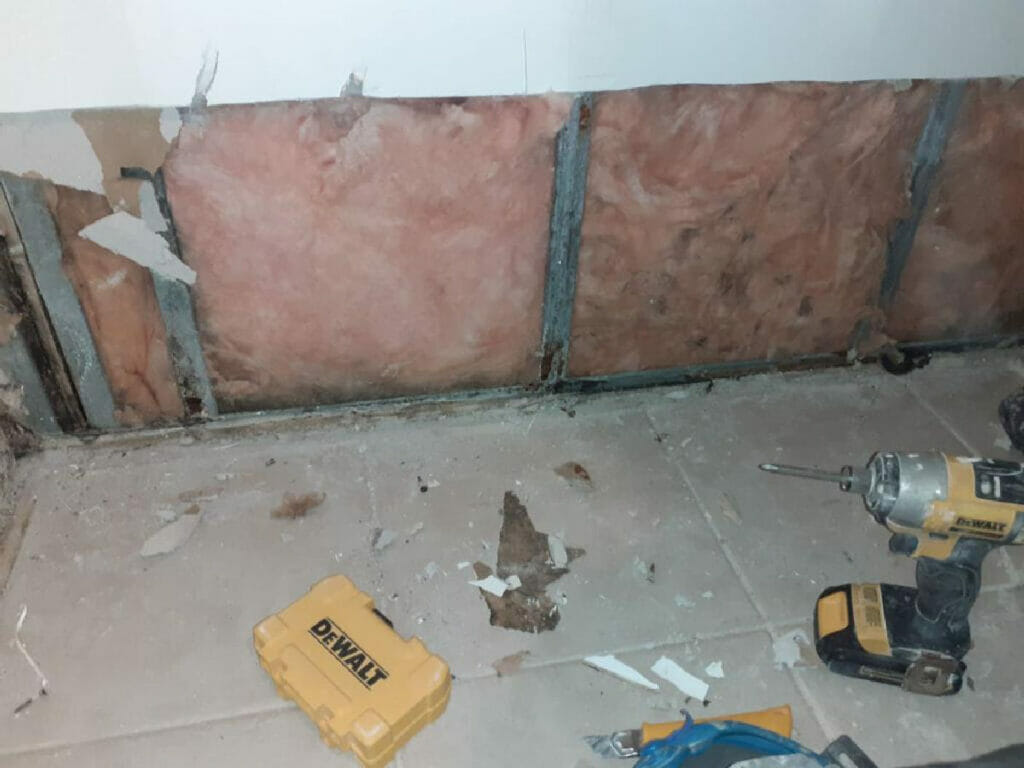 Desa Contracting, Restoration, and Janitorial Services is showing off a scrapped side bottom wall at a water damage area with a wall drill on the floor at a Toronto location.