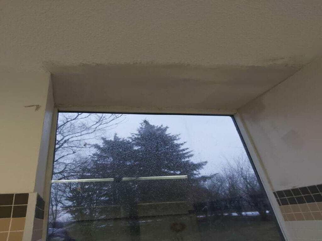 A water-damaged area on the ceiling wall and a fractured glass window at a Toronto residence are shown in this image from Desa Contracting, Restoration, and Janitorial Services.