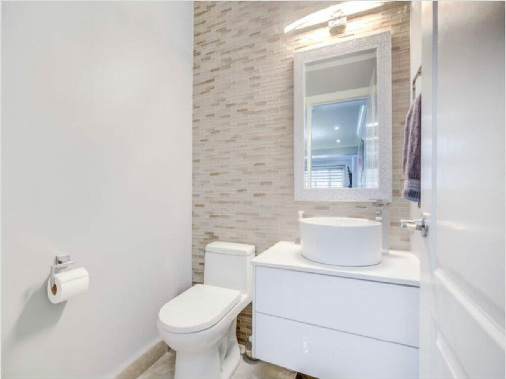 Desa Contracting and Restoration's Toronto home restoration includes a bathroom with a mirror, a beautiful washbasin and a toilet pot.