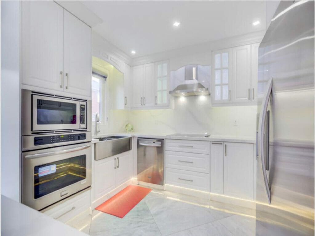 Desa Contracting and Restoration's kitchen remodel in Toronto includes the incorporation of pot lights, cabinets, a spacious refrigerator, and a microwave.