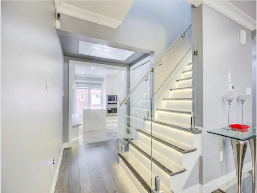 In Desa Contracting and Restoration's renovation of a home in Toronto, they have incorporated a staircase adorned with LED lights, along with a kitchen and a side table.