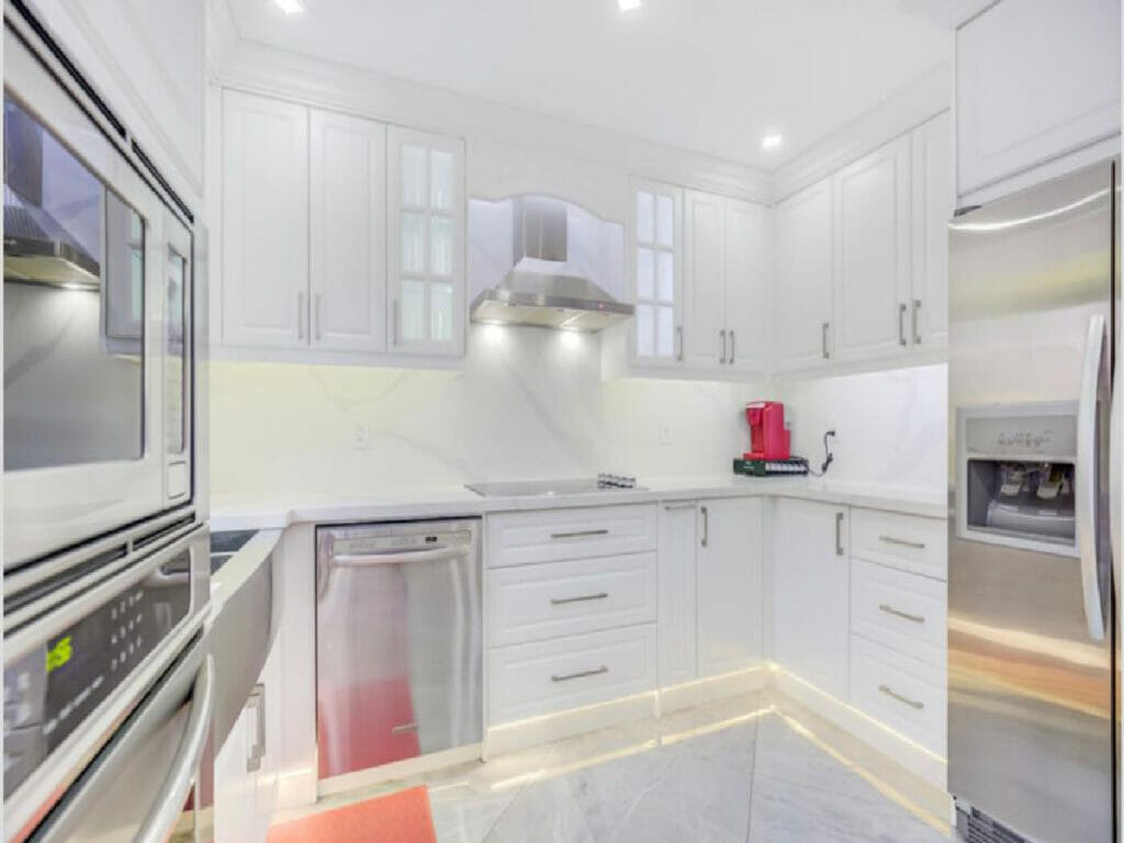 Desa Contracting and Restoration's Toronto kitchen restoration features pot lights, cabinets, a large fridge, and a microwave.