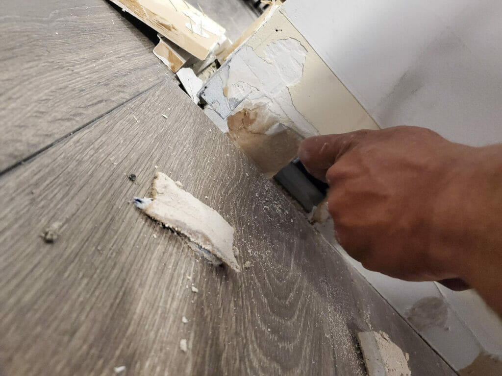 A Desa Contracting, Restoration, and Janitorial Services specialist scrapes a wall at the Residence in Toronto as they work on water damage restoration.
